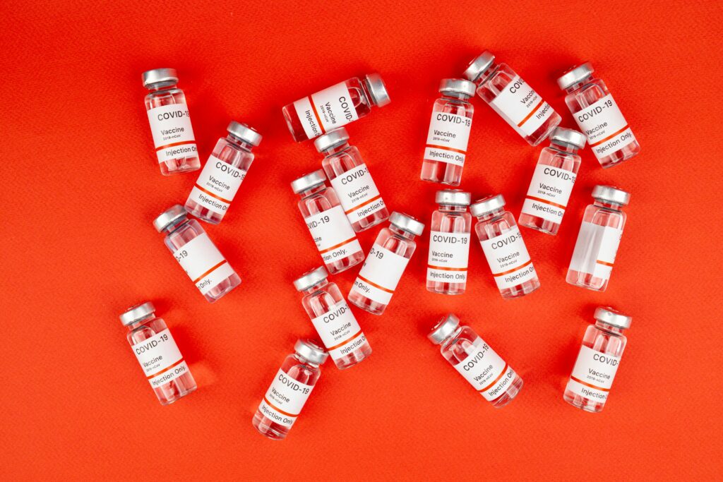 vacuna, COVID-19, salud pública, prevención, viales, medicina, fondo rojo.