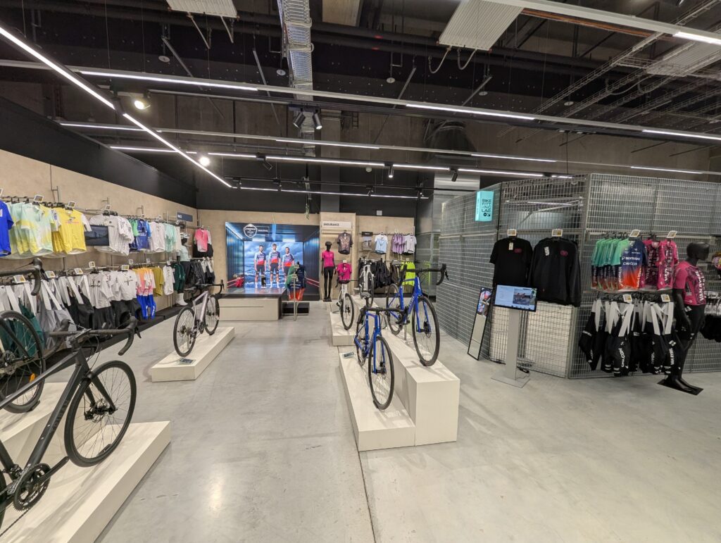 Espacio comercial panorámico de Van Rysel mostrando bicicletas de exposición y el acceso lateral al Bike Fitting Lab.